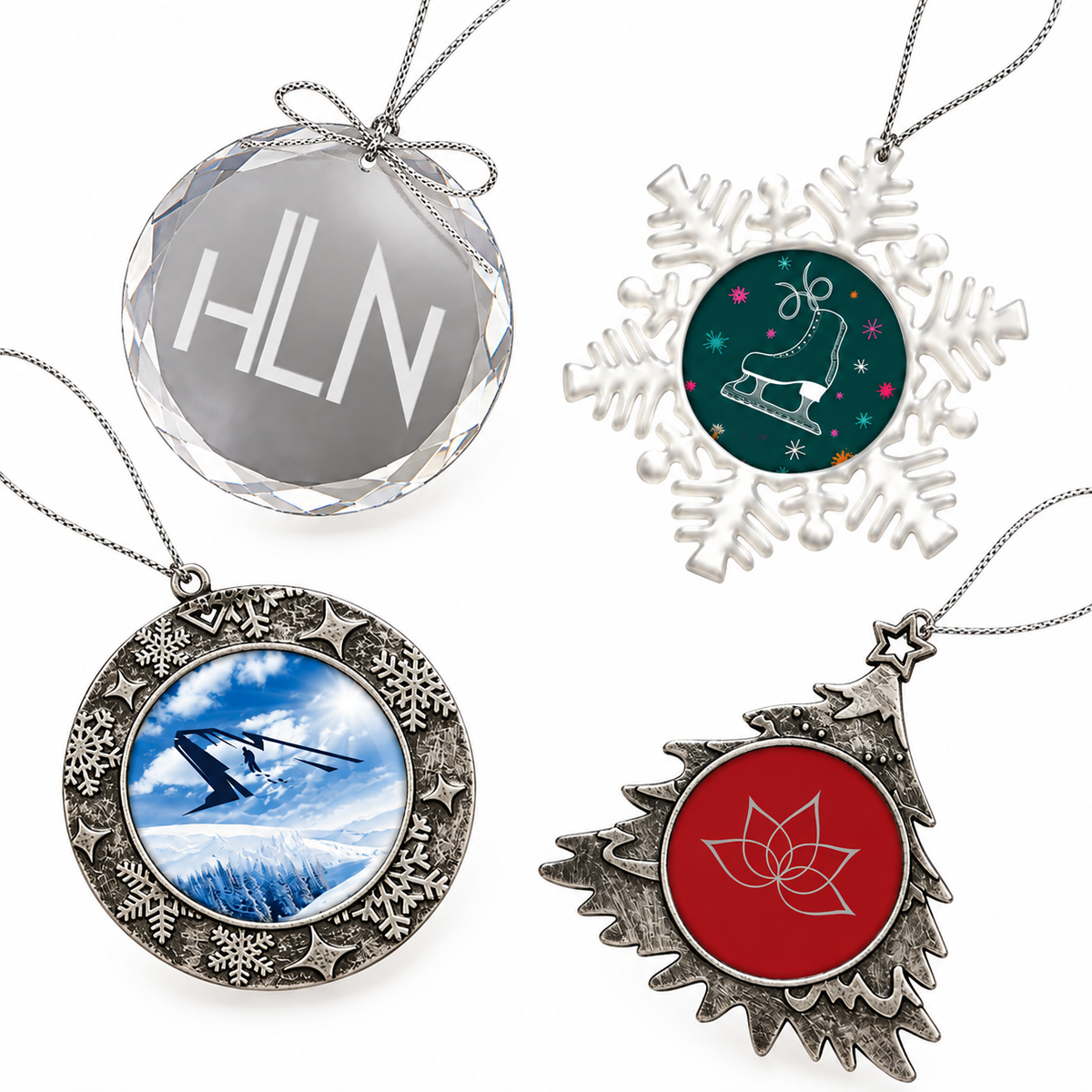 Four silver-toned holiday pendant necklaces arranged on a white background: a faceted round pendant with the letters HLN, a snowflake pendant with a green ice skate design, an ornate circular pendant with a snowy mountain scene, and a Christmas tree pendant with a red lotus flower design.